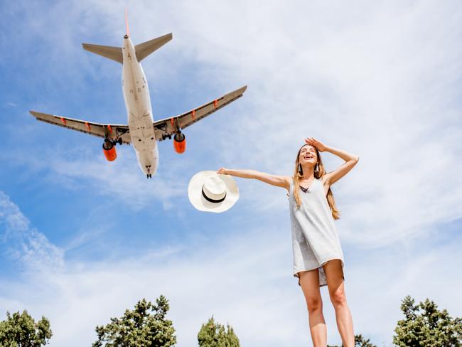 ESCAPE: Young and happy woman enjoying the airplane flying in the sky. Picture: Istock