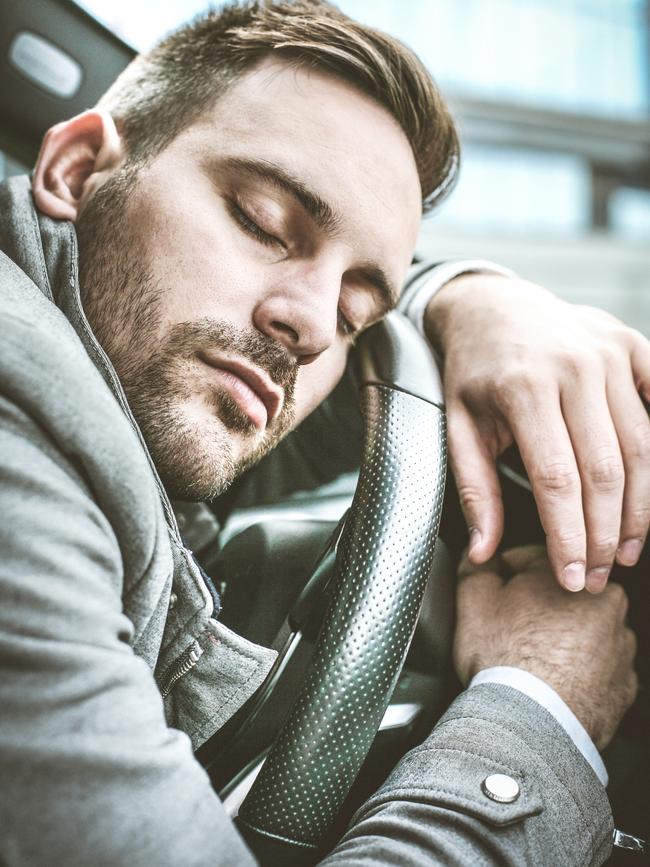 A man takes a powernap in his car. Stock photo.