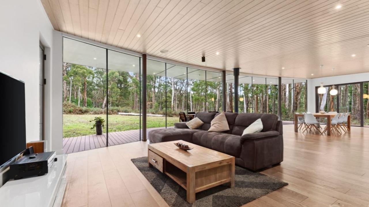 The open plan living area in the main house looks out onto a lush private forest