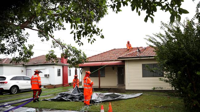 SES workers put a tarp on damaged house in Chester Hill, where a mini tornado struck on Saturday morning. Picture: Damian Shaw