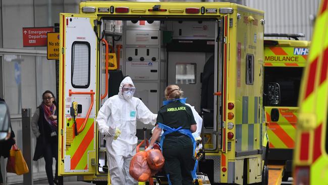 Ambulance staff wearing personal protective equipment (PPE) help a patient from an ambulance into The Royal London Hospital in east London.