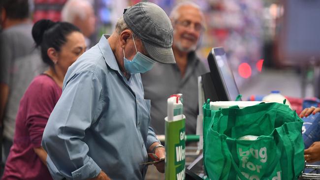 A shopper wears a face mask as a preventive measure against coronavirus at a Woolworths checkout. Picture: AAP/James Ross