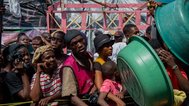 People displaced by gang violence wait for food at a refugee camp in Port-au-Prince last month. Picture: AFP