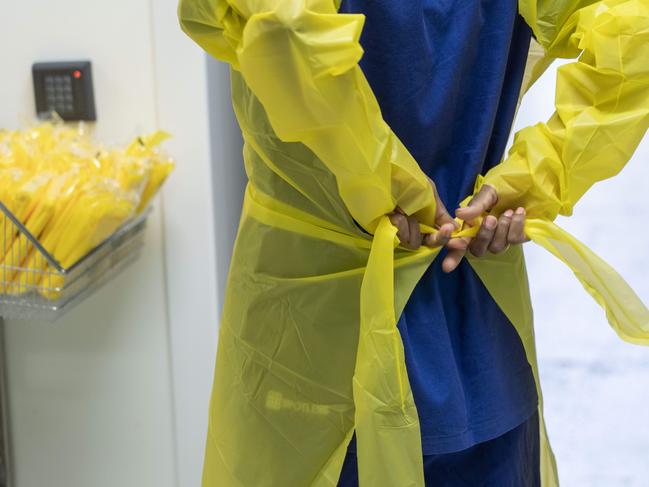 A nurse putting on full PPE in the administration area before going into the hot zone of the clinic. Image Matthew Vasilescu