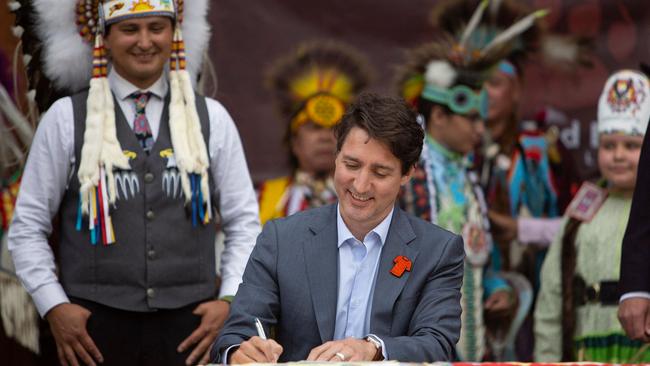 Justin Trudeau, flanked by Chief Cadmus Delorme, signs the first-of-its-kind deal in Cowessess on Tuesday. Picture: AFP