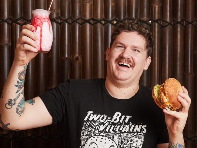 Two Bit Villians diner owner Liam Hughes with a popular vegan option — a seitan buffalo “chicken” burger. Picture: Matt Loxton