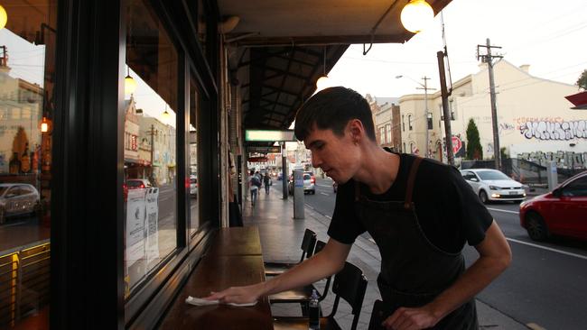 Waiter Aidan Carstens sanitises the front entrance at Hartsyard restaurant in Sydney’s Newtown in preparation for their first round of diners after the easing of restrictions. Picture: Getty Images