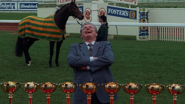 1996: Cups King Bart Cumming at Flemington with his nine Melbourne Cups. The horse in the background, Saintly, duly saluted the following week to give him his 10th. He finished with 12 before his death in 2015. Picture: Bruce Howard