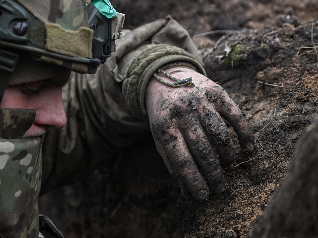 A Ukrainian serviceman takes cover in a trench during shelling next to a 105mm howitzer near the city of Bakhmut. Picture: AFP