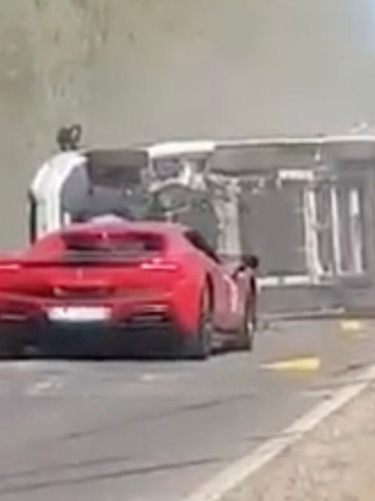The Ferrari caught on fire behind the flipped camper van after the brutal collision. Picture: Jam Press