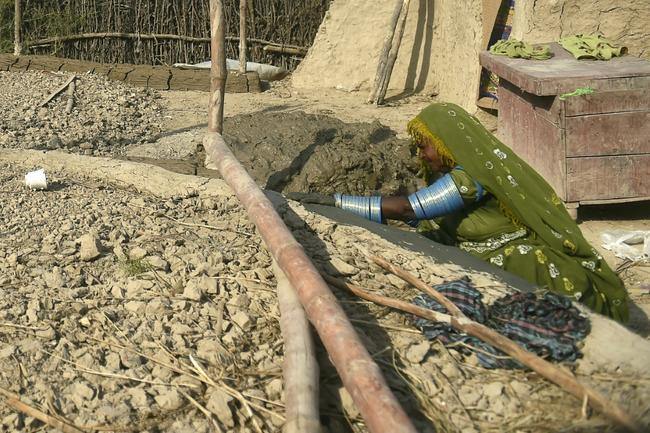 A woman buildis a flood-resistant hut at Sanjar Chang village, Sindh province