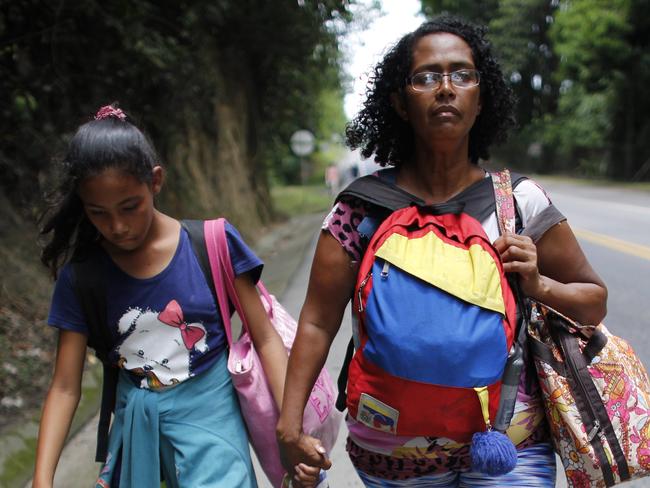 In this Sept. 2, 2018 photo, Venezuelan Sandra Cadiz holds the hand of her 10-year-old daughter Angelis as they walk on the shoulder of the road during their journey to Peru, near Dagota, Colombia. When Sandra Cadiz began struggling to feed her daughter, she knew it was time to leave Venezuela. (AP Photo/Ariana Cubillos)