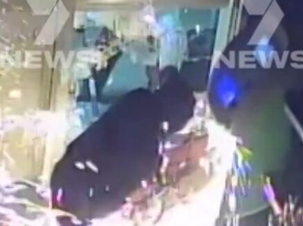 security vision of the moment two would-be thieves use an angle grinder to try to raid a service station's ATM at Golden Grove. As police swooped on the thugs, one officer was taken down by the car. Picture: 7NEWS