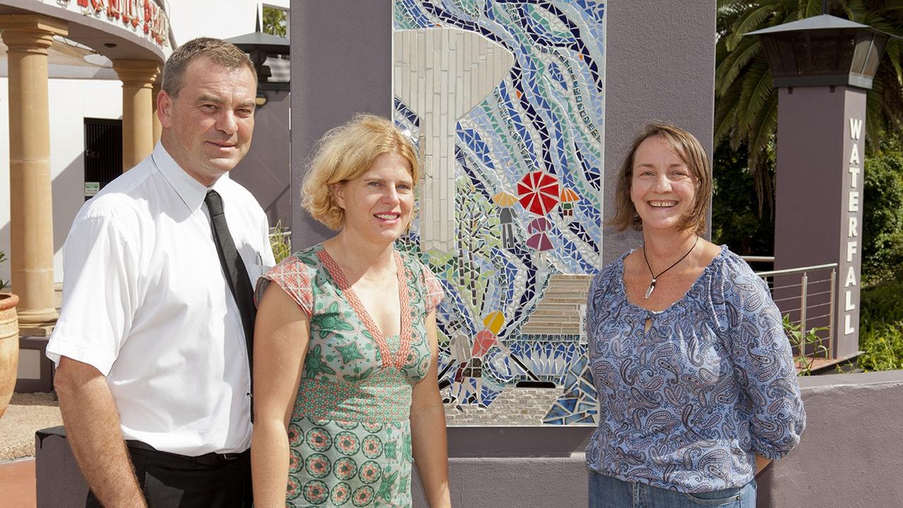 Toowoomba Arts Council's Splashing Back Art Trail has been selected as a finalist in two categories for the National Street Art Awards in 2020. Kenny Kristensen (left) with Catherine Kristensen (middle) from Picnic Point Toowoomba with artist Kim Besley Scott in front of her stunning mosaic of the water tower. Picture: Contributed