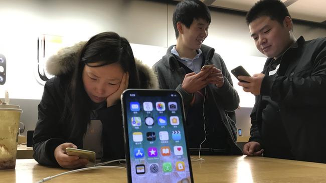 Shoppers check out iPhones at an Apple store in Beijing. Pic: AP