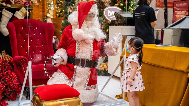 Santa Claus talks to a girl through a transparent barrier at a shopping centre in Kuala Lumpur, Malaysia. Picture: AFP