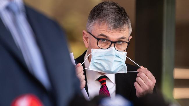 Dr Jeremy McAnulty removing his mask at a press conference in Sydney. Picture: James Gourley