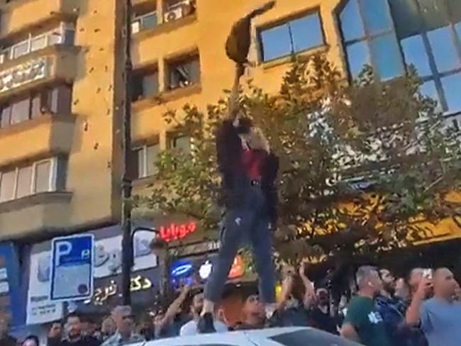 This image grab taken from a UGC video made vailable on September 23, 2022, shows a woman waving a hijab as she stands atop a car, during a protest in Mashhad in northeastern Iran, on September 20, 2022. - Protests have spread across Iran over the death of Mahsa Amini after the young woman was arrested by morality police, with a total of six demonstrators killed in a crackdown according to a rights group. (Photo by UGC / AFP) / XGTY /  RESTRICTED TO EDITORIAL USE - MANDATORY CREDIT :ESN - NO RESALE -  - NO MARKETING NO ADVERTISING CAMPAIGNS  -NO ACCESS ISRAEL MEDIA/PERSIAN LANGUAGE TV STATIONS OUTSIDE IRAN/ STRICTLY NO ACCESS BBC PERSIAN/ VOA PERSIAN/ MANOTO-1 TV/ IRAN INTERNATIONAL/RADIO FARDA / BEST QUALITY AVAILABLE