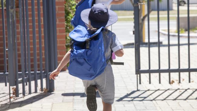 Two school children running out the school gate at the end of the day.