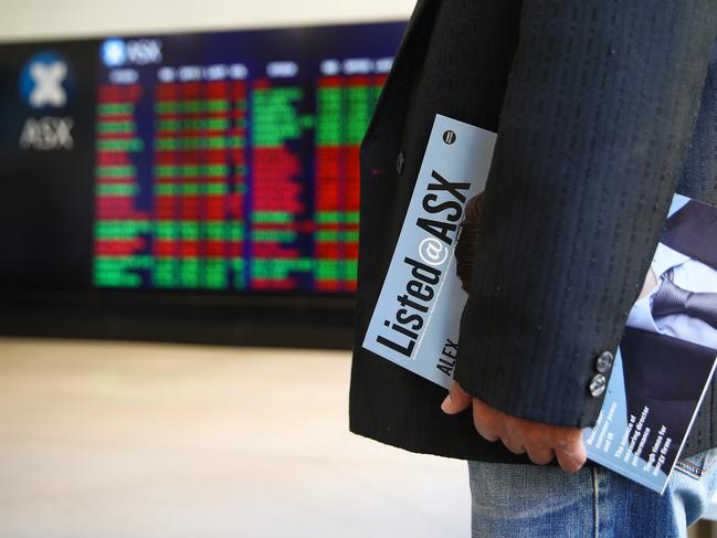 A man holds a Listed@ASX magazine while looking at an electronic board displaying stock information at the Australian Securities Exchange, operated by ASX Ltd., in Sydney, Australia, on Tuesday, Feb. 6, 2018. Global equity markets are in retreat after Wall Street losses that began in the final session of last week worsened on Monday, with the Dow Jones Industrial Average posting its biggest intraday point drop in history. Photgrapher: Brendon Thorne/Bloomberg