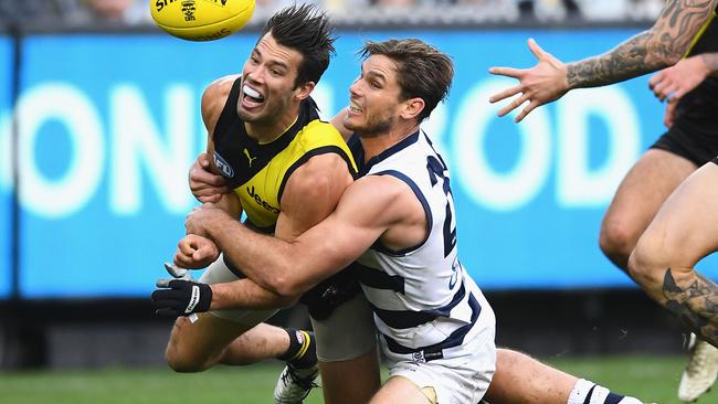 Alex Rance handballs whilst being tackled by Tom Hawkins.