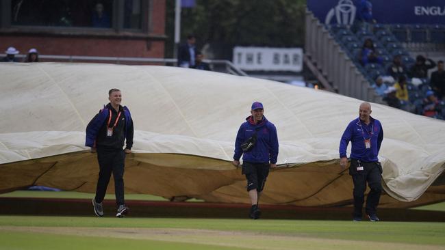 Hard working... ground staff manoeuvre covers as rain stops in Manchester. Picture: AFP