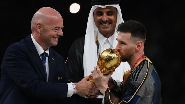 Lionel Messi kisses the World Cup trophy alongside FIFA President Gianni Infantino. Photo by FRANCK FIFE / AFP.