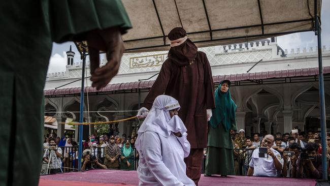 An Acehnese woman is caned in public last month from an executor known as 'algojo' for spending time with a man who is not her husband in Banda Aceh, Indonesia. Picture: Getty Images