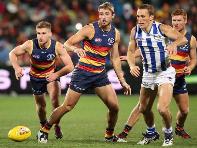 Daniel Talia and Rory Laird of the Crows chase down a loose ball in front of Drew Petrie of the Kangaroos.