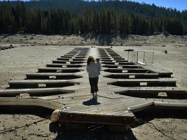 Marina owner Mitzi Richards carries her granddaughter as they walk on their boat dock at the dried up lake bed of Huntington Lake, which is at only 30 per cent capacity as a severe drought continues to affect California. Picture: Mark Ralston