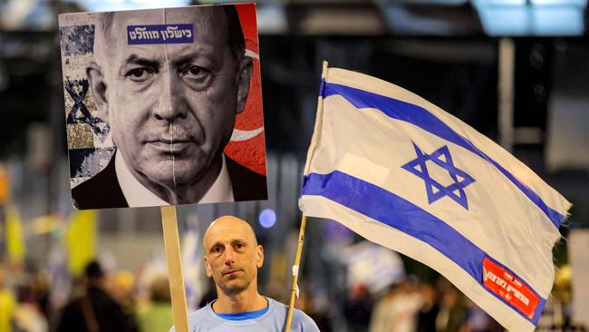 An anti-government protester in Tel Aviv in April, holding a sign depicting a collage of the faces of Israeli PM Benjamin Netanyahu and Turkish President Recep Tayyip Erdogan. Picture: Jack Guez / AFP