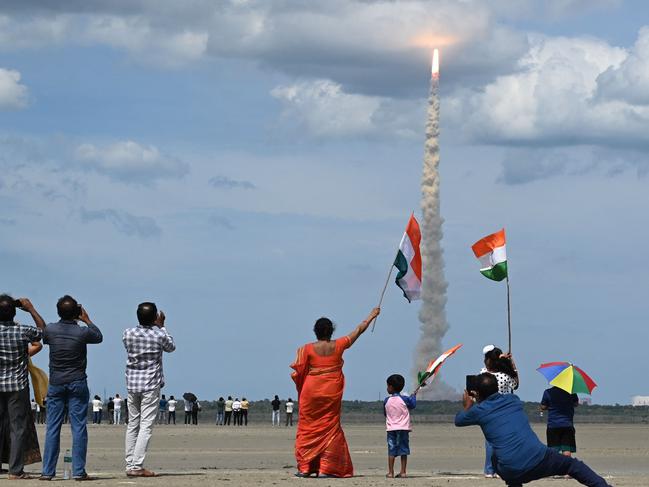 Fly me to the moon and back: Fans wave flags as India launches a rocket in an attempt to land an unmanned spacecraft on the surface of the moon. Picture: R.Satish Babu/AFP