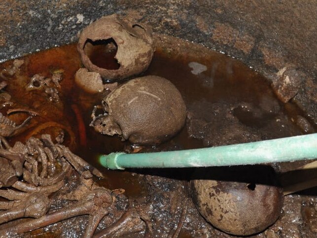 A handout picture released on July 19, 2018 by the Egyptian Antiques ministry shows skeletons in the black granite sarcophagus uncovered early this month in the Sidi Gaber district of Alexandria, filled with sewage water. Skeletons are believed to be three warriors as one of the skulls bear a wound resulted from the hit of an arrow. / AFP PHOTO / EGYPTIAN ANTIQUITIES MINISTRY / -