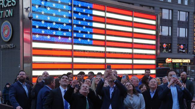 People take photos of the Nasdaq headquarters in Times Square, as Nasdaq fell nearly 4 per cent. (Photo by Bryan R. SMITH / AFP)