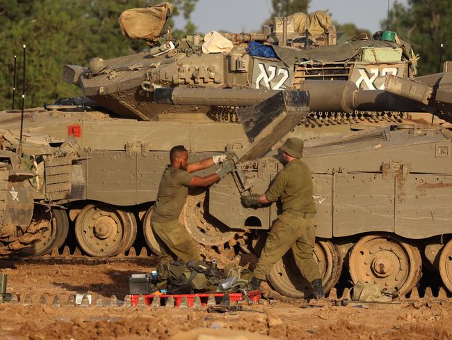 A picture taken from southern Israel near the border with the Gaza Strip on November 20, 2023, shows an Israeli soldier working on a tank near the Palestinian enclave, amid ongoing battles between Israel and the Palestinian Hamas movement. (Photo by GIL COHEN-MAGEN / AFP)