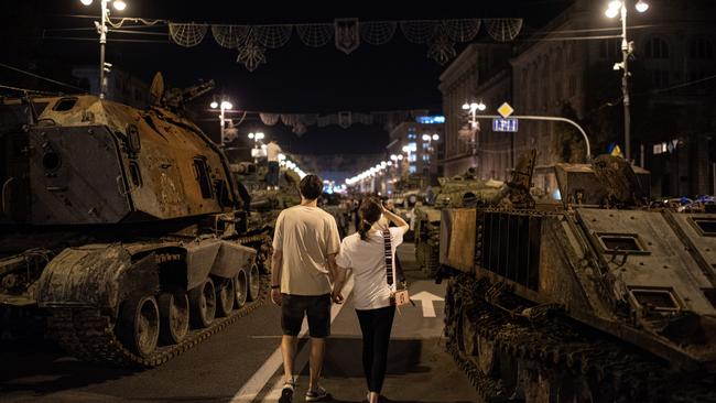 A couple walks by burnt-out Russian military vehicles in Kyiv. Picture: Getty Images