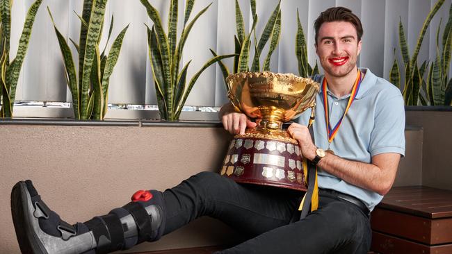 Glenelg’s Liam McBean, with his damaged right foot in a moon boot, enjoys the fruits of his labour at Marion Hotel on Monday. Picture: MATT LOXTON