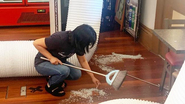 Gawler cafe owner Marie-Anne San Gabriel cleaning up broken glass. Picture: George Yankovich