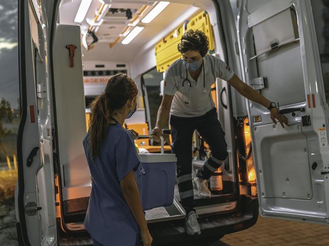 The life saving service paramedic healthcare worker man and nurse woman wearing a surgical face mask working nightshift rushing and delivering a special bag containing a internal human organ for transplantation or donation and transportation by ambulance car during the covid19 pandemic after coronavirus quarantine and lockdown