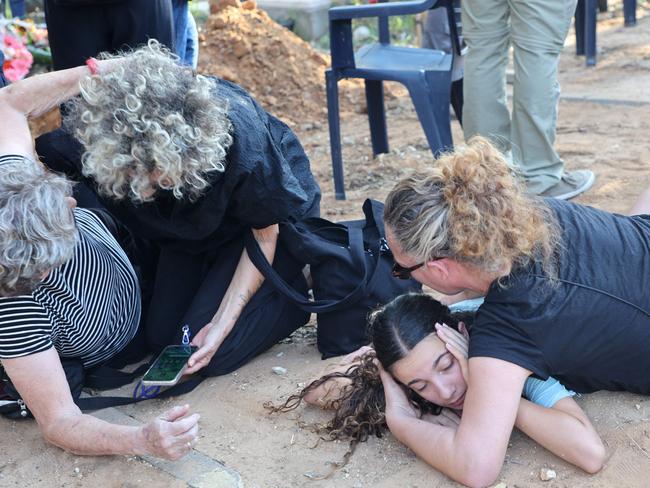 Mourners duck for cover upon hearing sirens warning of incoming rockets during the funeral of Tom Godo, killed during the attack by Palestinian Hamas militants on the Kibbutz Kisuffim on October 7. Picture: Gil Cohen-Magen/AFP