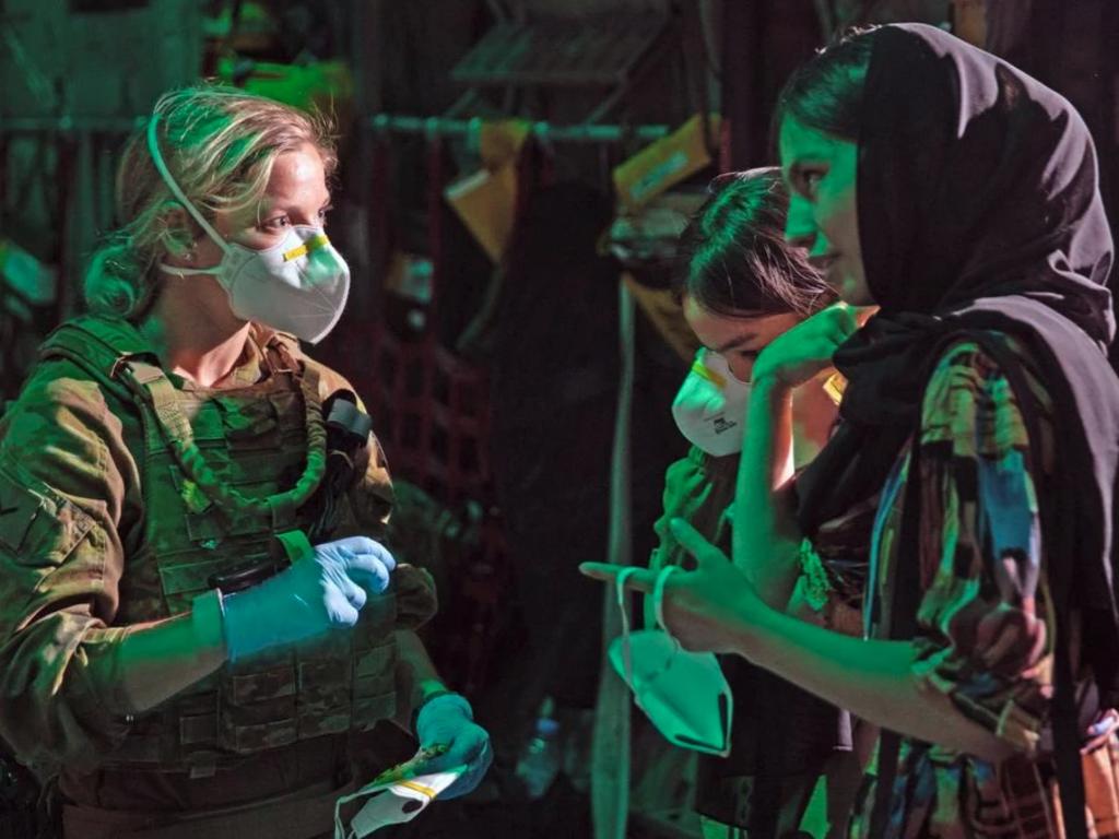 RAAF medic Leading Aircraftwoman Hayley Daniel provides masks to evacuees before they board the first Australian rescue flight from Kabul. Picture: ADF