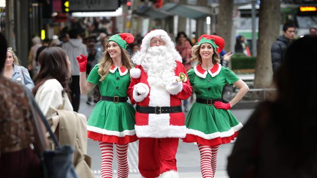 Santa with elves Ellie and Ellen walk among the shoppers in the Bourke Street Mall. Picture: David Caird