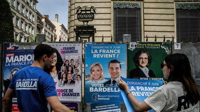 Rassemblement National (RN) party volunteers paste campaign posters of Jordan Bardella in Lyon. Picture: AFP.