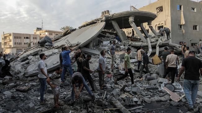 People search through buildings, destroyed during Israeli airstrikes in the southern Gaza Strip on Monday. Picture: Getty Images