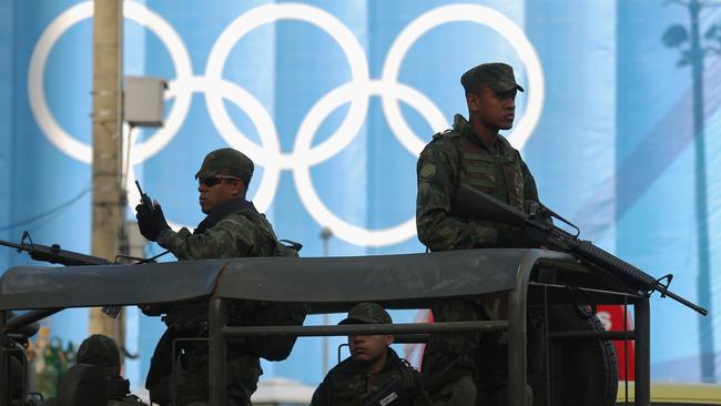 RIO DE JANEIRO, BRAZIL - AUGUST 04: Brazilian soldiers keep watch in front of Olympic rings displayed at the beach volleyball venue ahead of the arrival of the Olympic torch relay in Copacabana on August 4, 2016 in Rio de Janeiro, Brazil. The Rio 2016 Olympic Games commence on August 5. (Photo by Mario Tama/Getty Images)