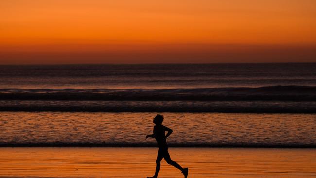 A runner on a pre-dawn run beach at Lorne.