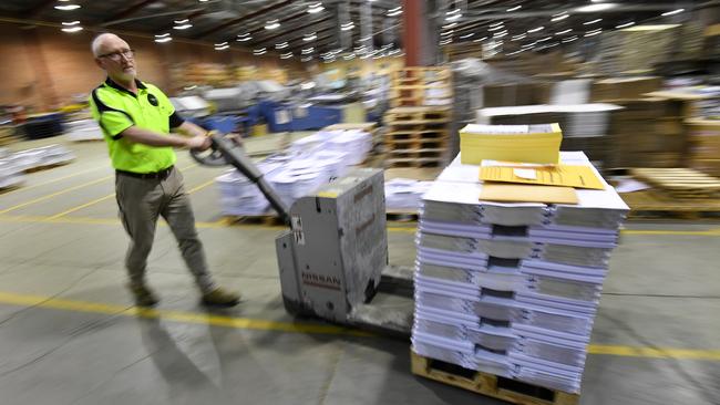 A man moves a stack of the Budget papers at Canprint in Canberra. Picture: AAP