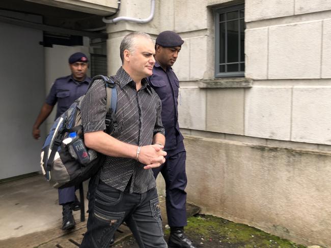 John Nikolic being escorted by a police officer after day five of their hearing at the Suva High Court. PHOTO: Varanisese Bolatagane/News Corp Australia