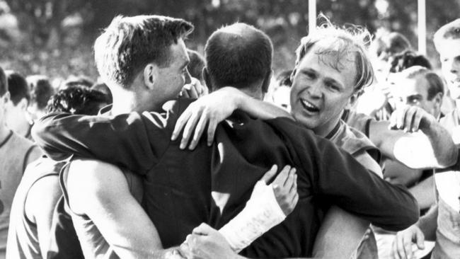 Unley High old scholars and Sturt players Malcolm “Emmy” Jones, John Halbert and Rick Schoff embrace after a Double Blues flag win.