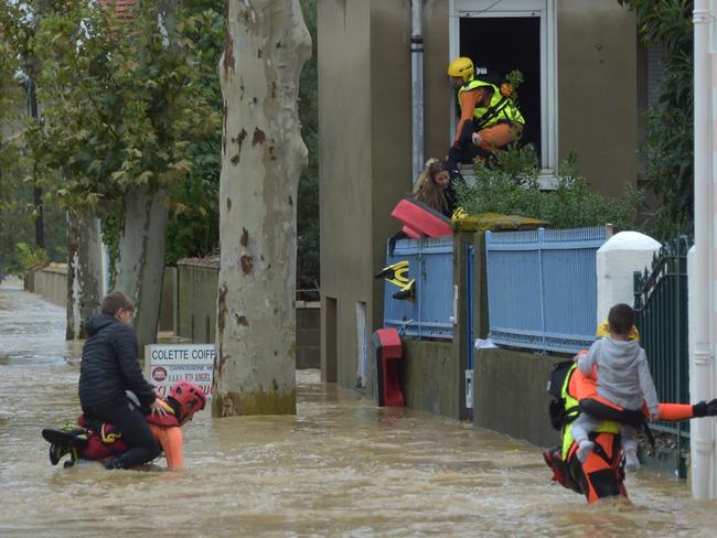 TOPSHOT - Firefighters help youngsters to evacuate in a flooded street during a rescue operation following heavy rains that saw rivers bursting banks on October 15, 2018 in Trebes, near Carcassone, southern France. - Six people died following storm and flash floods during the night of October 15 in the Aude department in southern France, authorities said. (Photo by Pascal PAVANI / AFP)